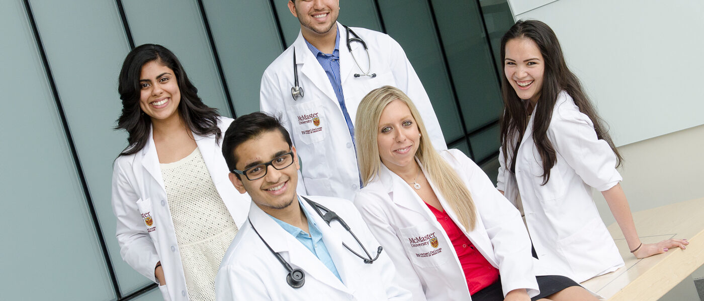 A group of smiling medical students in white coats